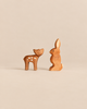 An Ostheimer Handmade Wooden Woodland Set featuring a handcrafted wooden fawn and rabbit facing each other.
