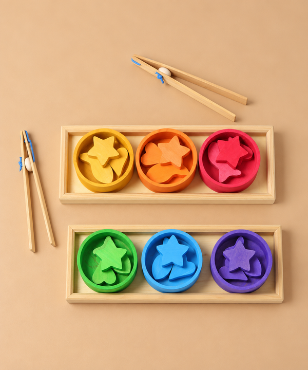 Grimm’s Sorting Game Rainbow Bowls with Tweezers, featuring two wooden trays, six colorful bowls, matching wooden star- and heart-shaped pieces, and two pairs of wooden tweezers.