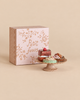 Three Maileg Miniature Cakes & Cake Stand pastries displayed on a small pedestal stand in front of a pink box labeled “Petit fours.”