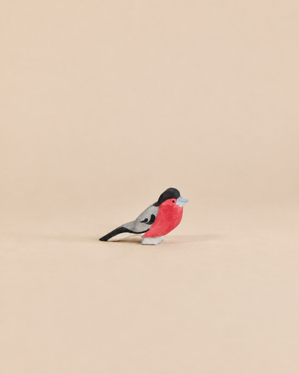 An Ostheimer Bird - Bullfinch handcrafted wooden toy with a red chest, black head, and grey wings, perfect for imaginative play.