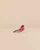 An Ostheimer Bird - Bullfinch handcrafted wooden toy with a red chest, black head, and grey wings, perfect for imaginative play.