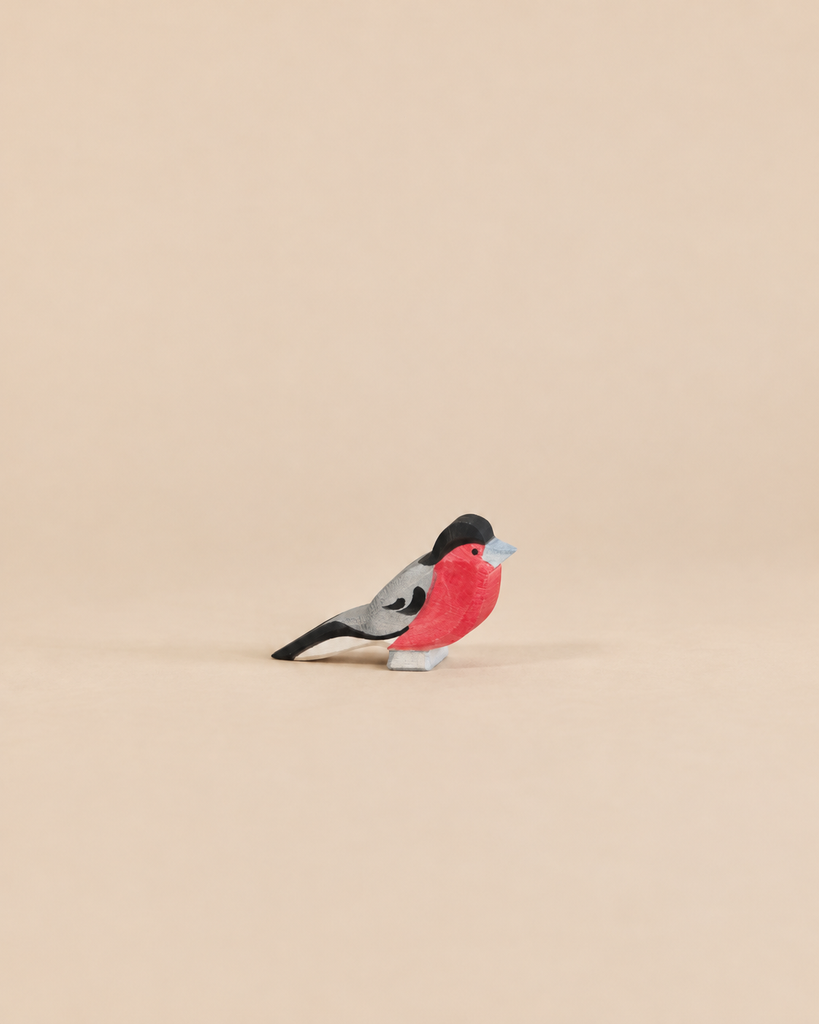 An Ostheimer Bird - Bullfinch handcrafted wooden toy with a red chest, black head, and grey wings, perfect for imaginative play.