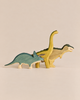 Handmade Holzwald Dinosaur Set featuring three wooden toys: a blue triceratops, a yellow long-necked dinosaur, and a tan and green T-Rex.