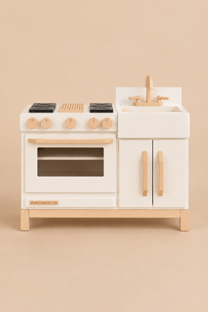 Milton & Goose Essential Play Kitchen in white wood with a stove, oven, sink, and natural wood accents for imaginative play.
