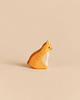 An Ostheimer Cat - Orange, Sitting, a small handcrafted wooden toy cat in a sitting position, painted orange with a white chest and green eyes, perfect for imaginative play.
