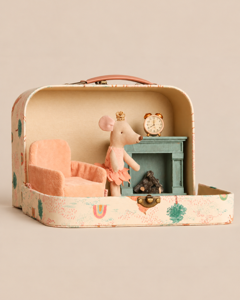 A Maileg On The Go Suitcase Set features a Maileg Princess Mouse in a tutu and crown, standing inside a suitcase furnished with a soft folding chair, a fireplace, and a clock.