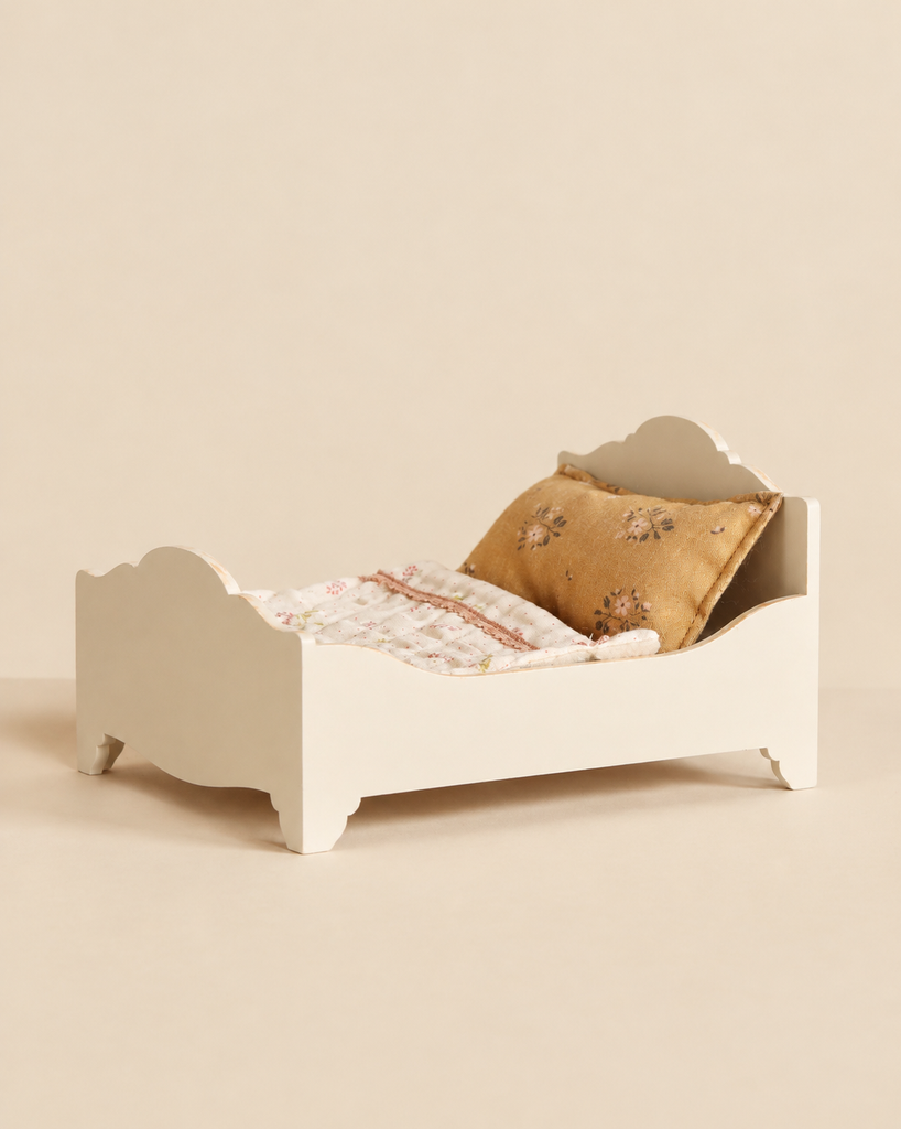 Maileg Wooden Bed, Mouse - Off White with a floral pillow and a quilted blanket.