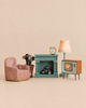 Maileg Living Room Set featuring a pink armchair, a potted plant, a teal fireplace with logs, an analog alarm clock, a table lamp, and a retro television set.