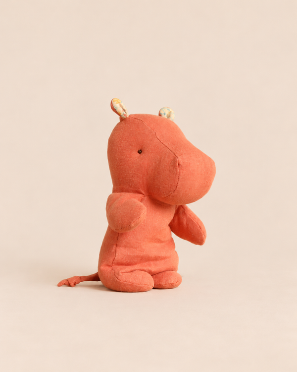 A small, dusty coral Maileg Safari Friends, Hippo, Small - Dusty Coral plush toy in a seated position.