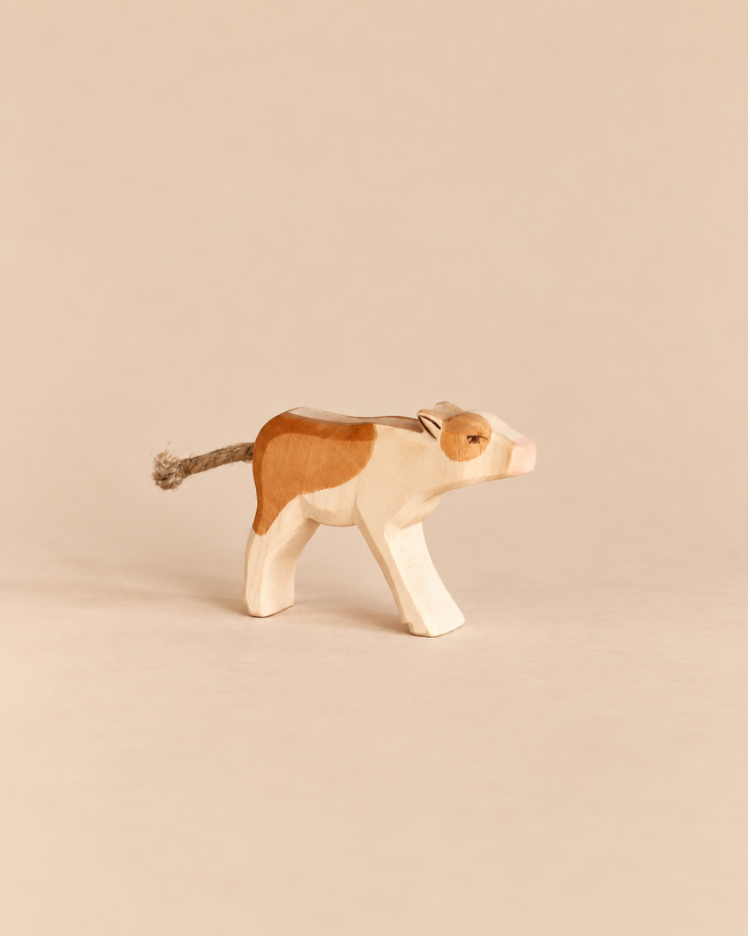 Ostheimer Calf - Drinking: a handcrafted wooden toy calf with brown patches and a rope tail, shown in a standing, lowered-head position.
