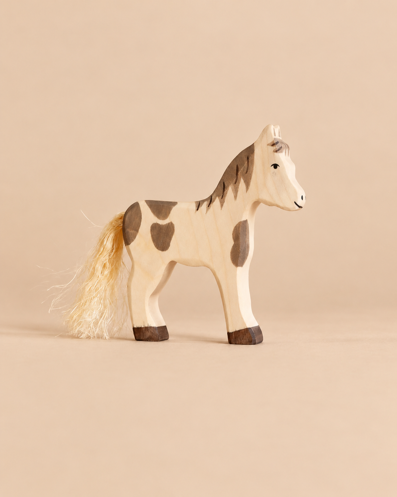 Holztiger Horse Foal, Standing: a handcrafted wooden toy horse with brown spots, a painted face, and a fibrous tail.