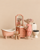 A Maileg Big Sister Bathroom Set features a Big Sister Mouse in pink polka-dot pajamas standing at a miniature vanity with a toothbrush, next to a pink clawfoot bathtub and a toilet.