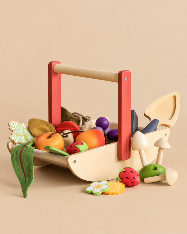 A Wild Wood Foraging Trug, which is a wooden toy basket filled with pretend play fruits, vegetables, and edible toy mushrooms, with a small wooden trowel resting inside.