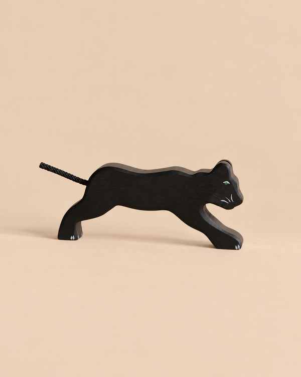 Holztiger Panther handcrafted wooden toy in a pouncing pose with a rope tail and green eyes.