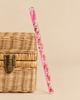 A Konges Sloejd Magical Glitter Wand - Pink Mix filled with liquid, pink glitter, and star-shaped confetti leaning against a small wicker box.