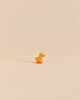 Small, handcrafted Ostheimer Duckling figurine with a yellow body and orange feet, perfect for imaginative play.