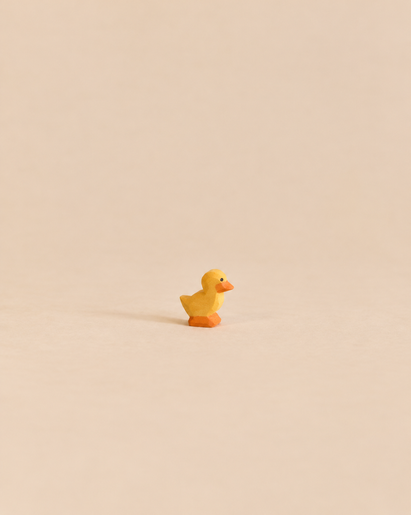 Small, handcrafted Ostheimer Duckling figurine with a yellow body and orange feet, perfect for imaginative play.