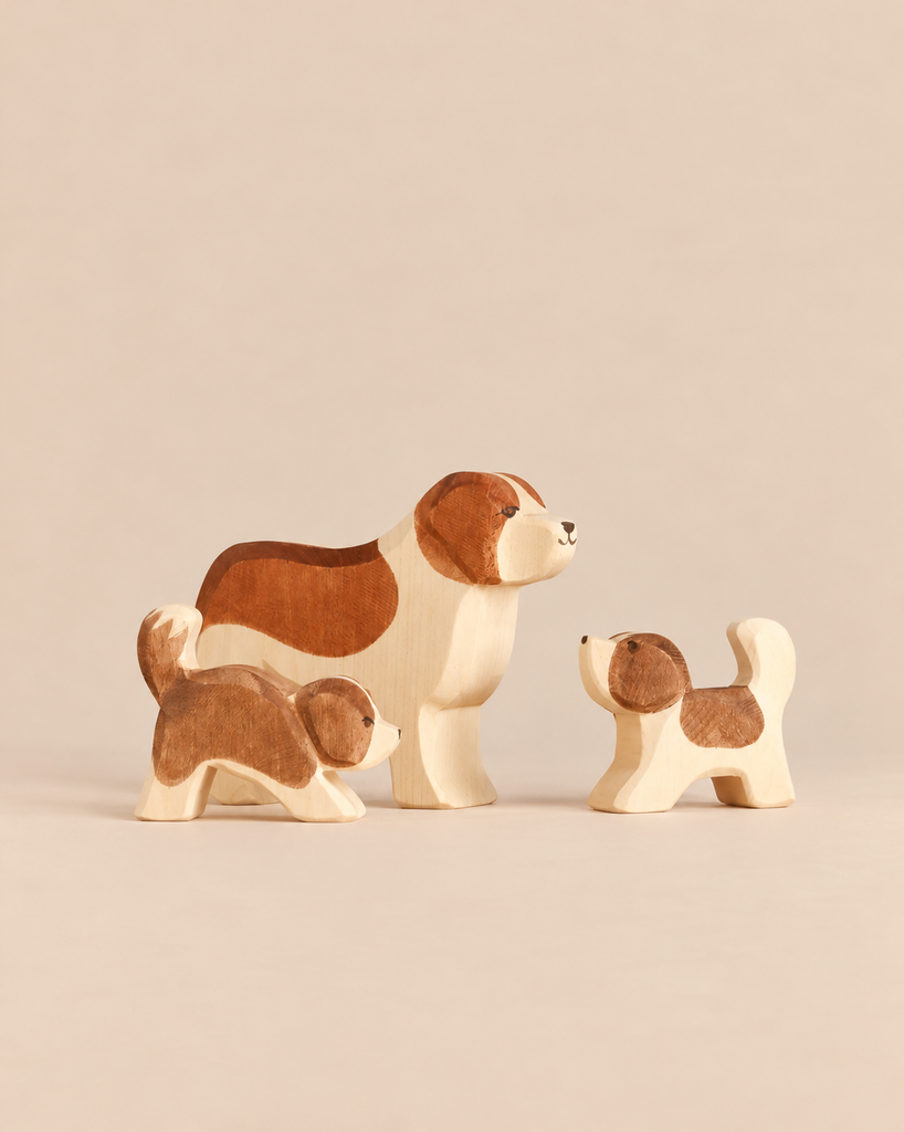 An Ostheimer Handmade Wooden Dog Family Set consisting of one large dog and two smaller puppies, all handcrafted with painted brown markings.