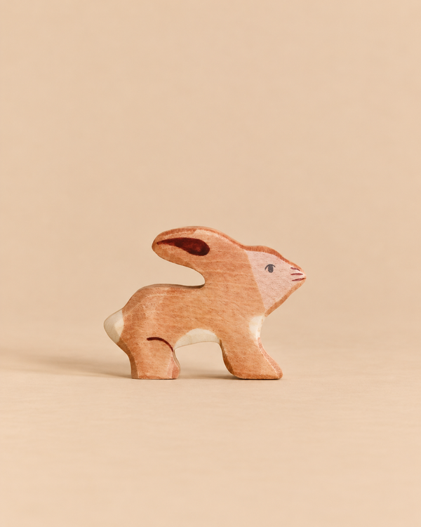 A Holztiger Rabbit handcrafted from wood in a crouching position, perfect for imaginative play.
