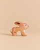 A Holztiger Rabbit handcrafted from wood in a crouching position, perfect for imaginative play.