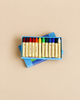 An open blue box of Stockmar Wax Stick Crayons Box - 12 Assorted, containing twelve non-toxic crayons in a spectrum of colors.