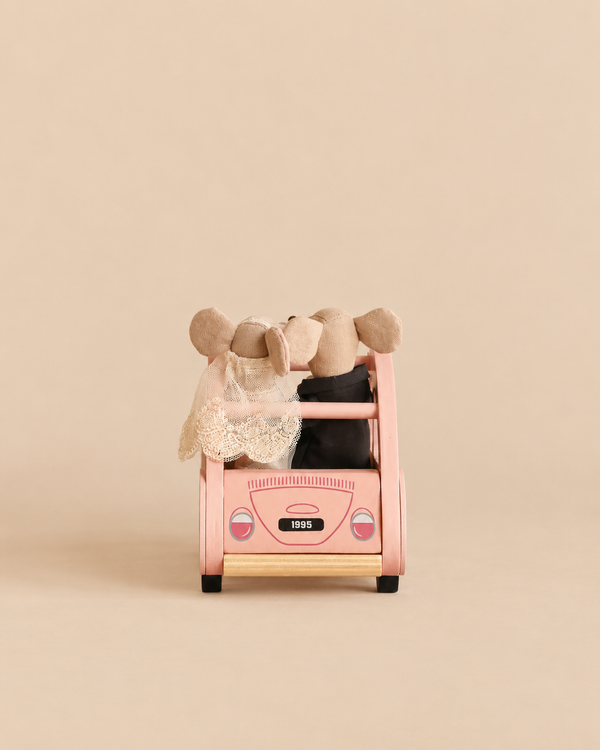 A Maileg Just-Married Set featuring a bride and groom mouse couple sitting in a small pink toy car.