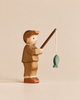 Handmade Holzwald Fisherman wooden toy wearing a cap and holding a rod with a small green fish hanging from a string.