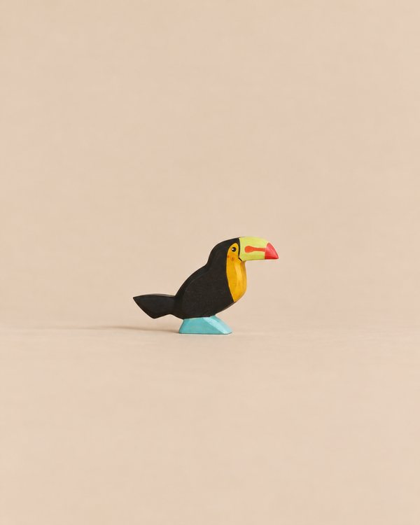 Handmade Holzwald Bird - Toucan figurine with a black body, yellow chest, and colorful beak standing on a blue base.
