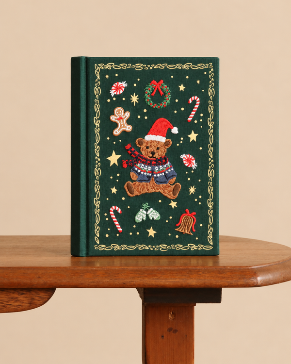 A Beary Christmas Embroidered Journal in dark green featuring holiday motifs, including a teddy bear in a Santa hat, a wreath, candy canes, and a gingerbread man.