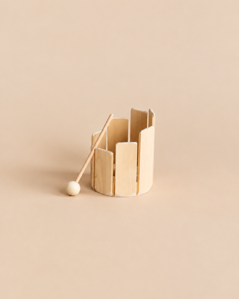 A handcrafted Auris Stir Xylophone Drum Wave consisting of a circular wooden frame with vertical slats and a matching mallet.