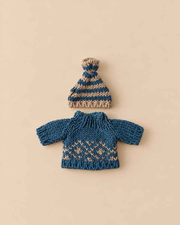 A blue and tan striped knit hat sits above a blue sweater featuring a tan Scandinavian geometric pattern for the Maileg Extra Clothing: Knitted Sweater And Hat for Dad Mouse.