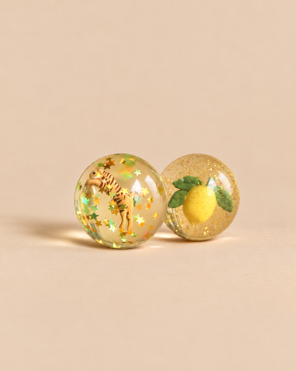 Konges Sloejd Glitter Bouncing Ball Set - Lemon & Tiger featuring two clear bouncy balls with glitter: one containing a tiger and star-shaped confetti, and the other containing a lemon with leaves.