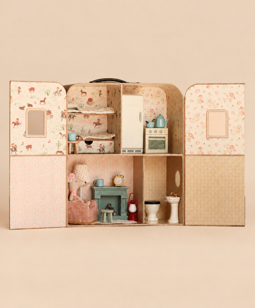 The Maileg Suitcasa Furnished Set opens to reveal a mouse dollhouse with two floors, a bed, kitchen appliances, a small chair, a table, and bathroom fixtures.