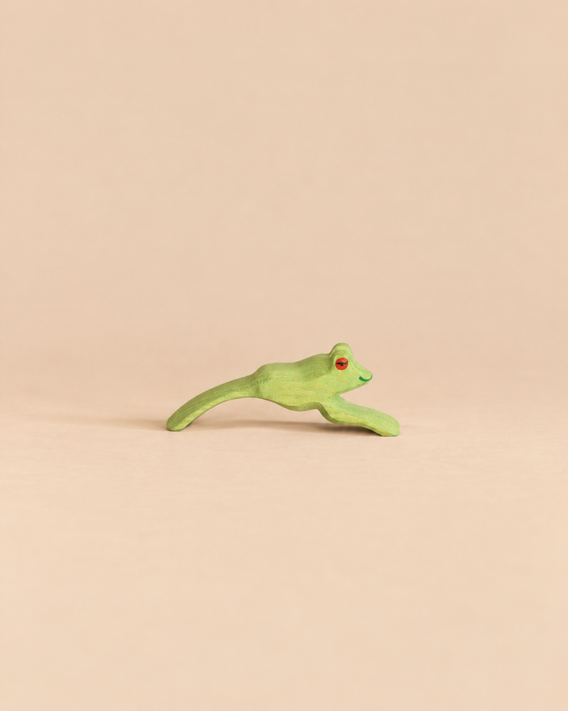 Ostheimer Jumping Frog handcrafted from wood, painted green with orange eyes in a jumping pose.