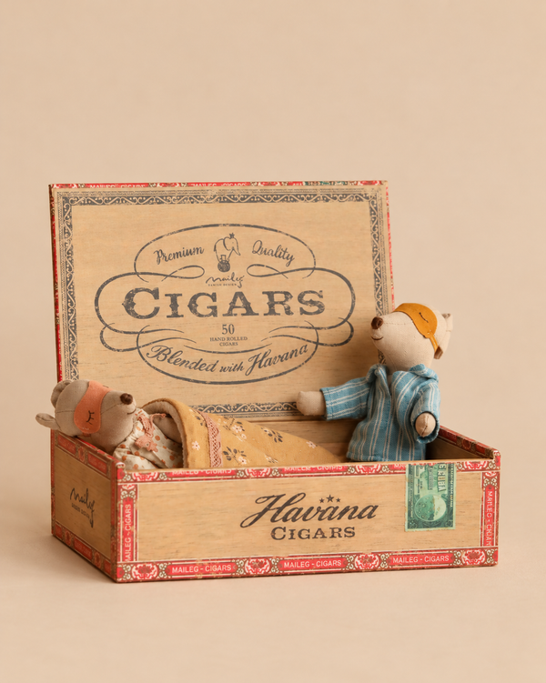 Maileg Mum & Dad Mice in Cigar Box featuring one mouse lying under a blanket and another sitting upright wearing a sleeping mask.