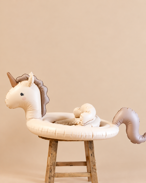 An Inflatable Baby Swim Ring - Unicorn - Final Sale, featuring a seat, perched on a wooden stool.