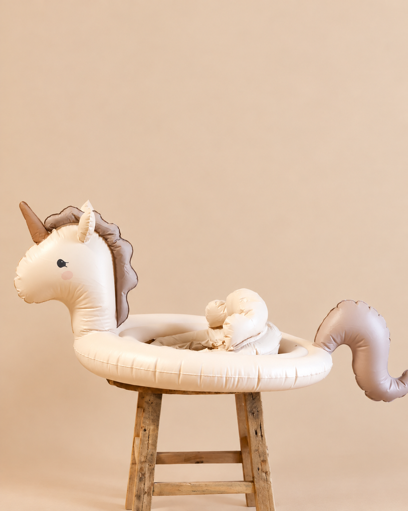 An Inflatable Baby Swim Ring - Unicorn - Final Sale, featuring a seat, perched on a wooden stool.