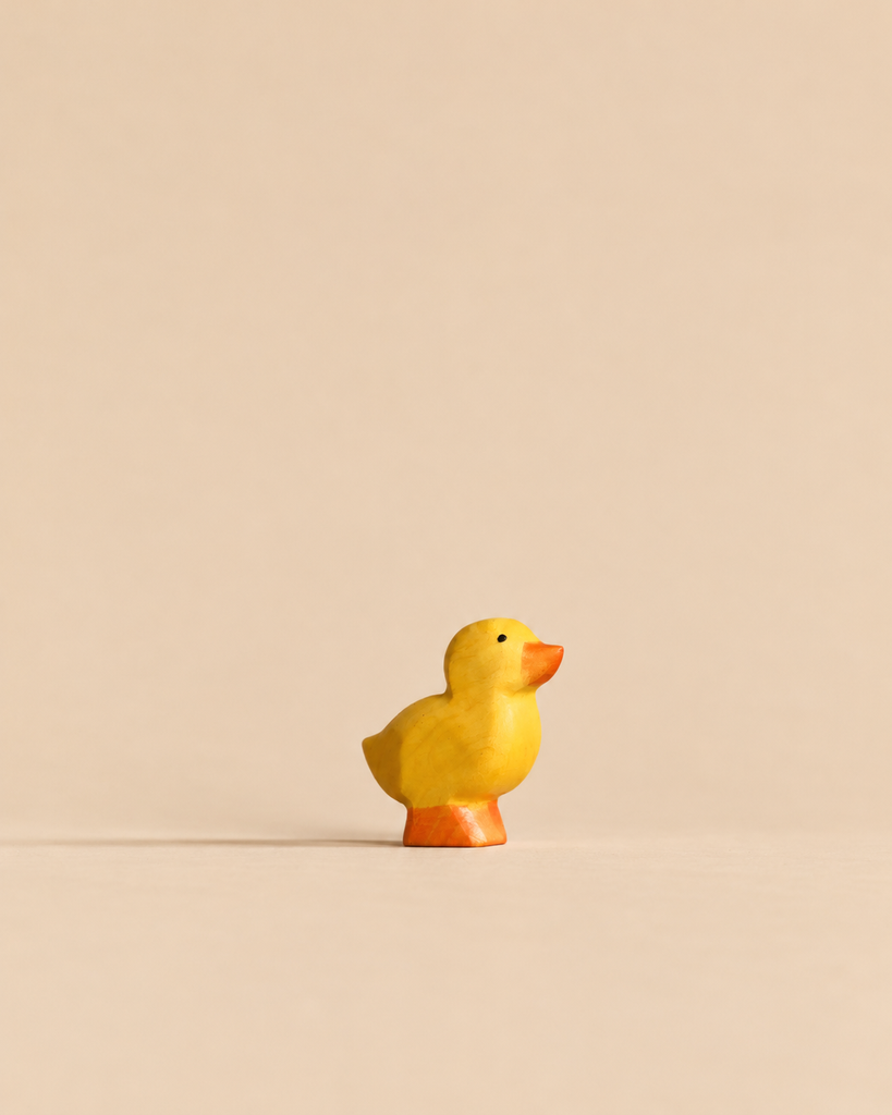 Handmade Holzwald Duckling, a small, sustainable wooden figurine with a yellow body and orange feet and beak.