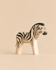 A handmade wooden zebra toy from the Handmade Holzwald Safari Animals Set with black painted stripes.