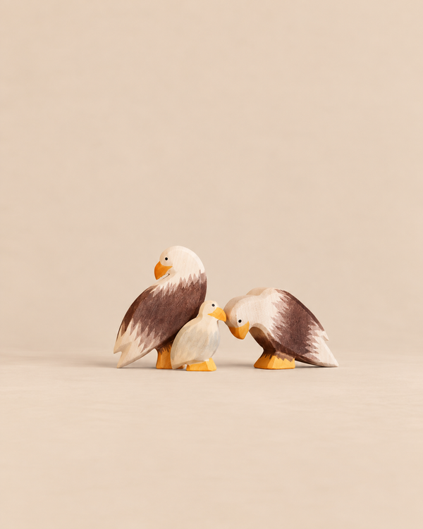 An Ostheimer Bald Eagle Family Set featuring two adult wooden eagle figures standing beside a smaller eagle chick.