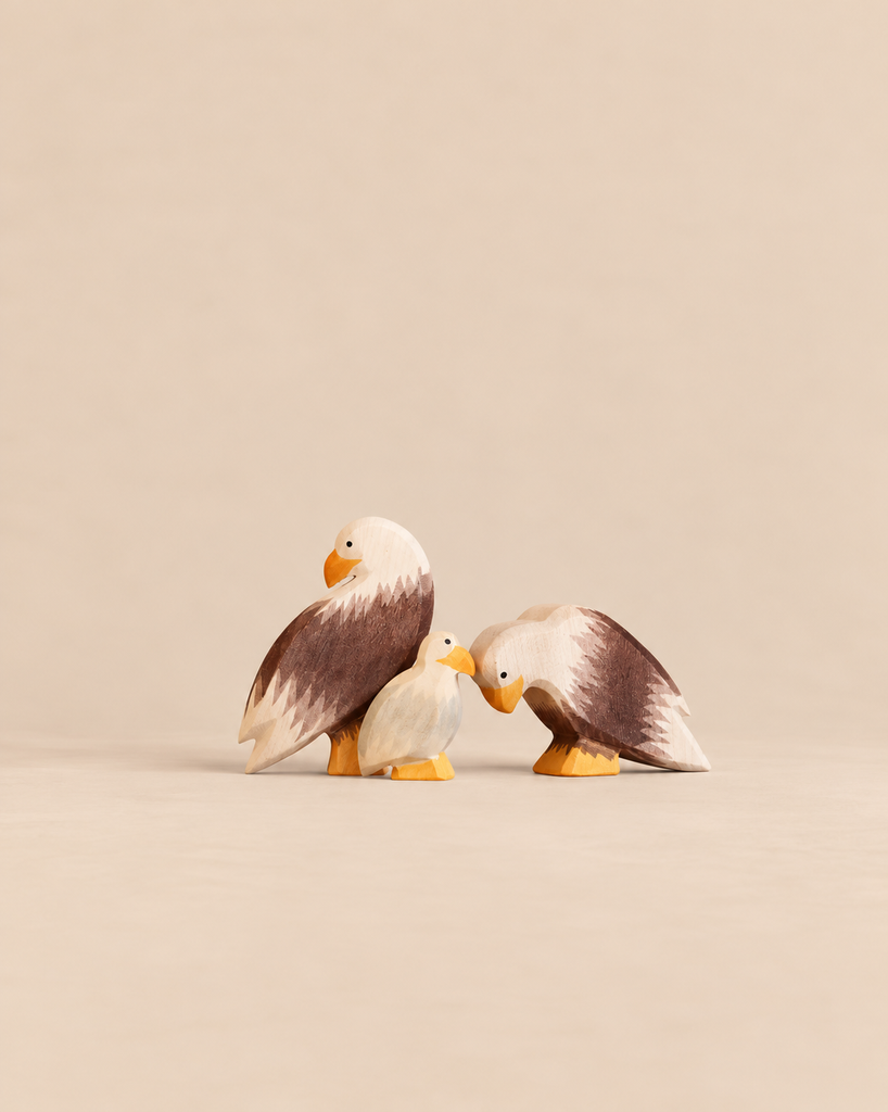 An Ostheimer Bald Eagle Family Set featuring two adult wooden eagle figures standing beside a smaller eagle chick.