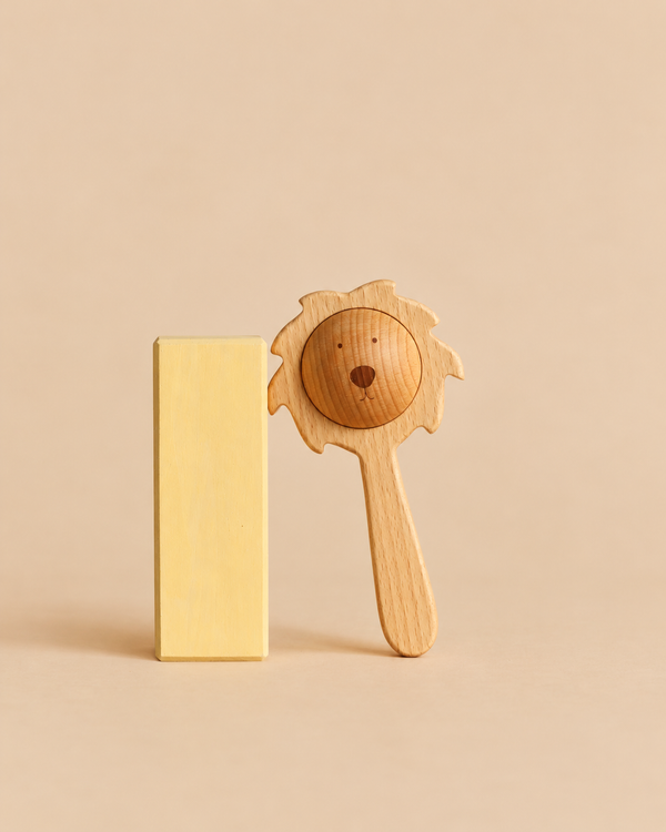 A Sabo Concept Lion Rattle - Natural made of wood standing next to a vertical yellow rectangular block.