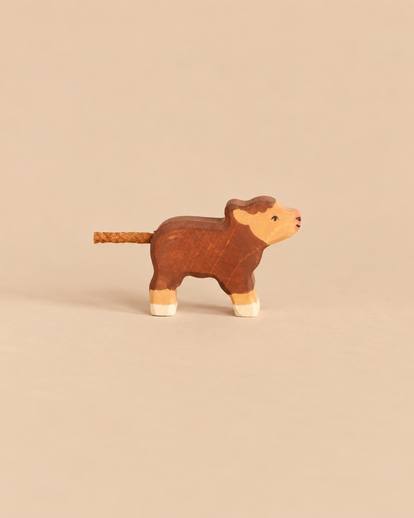 Handcrafted wooden Holztiger Higland Baby Cow, Small, featuring brown fur, a light-colored face, and a rope tail.