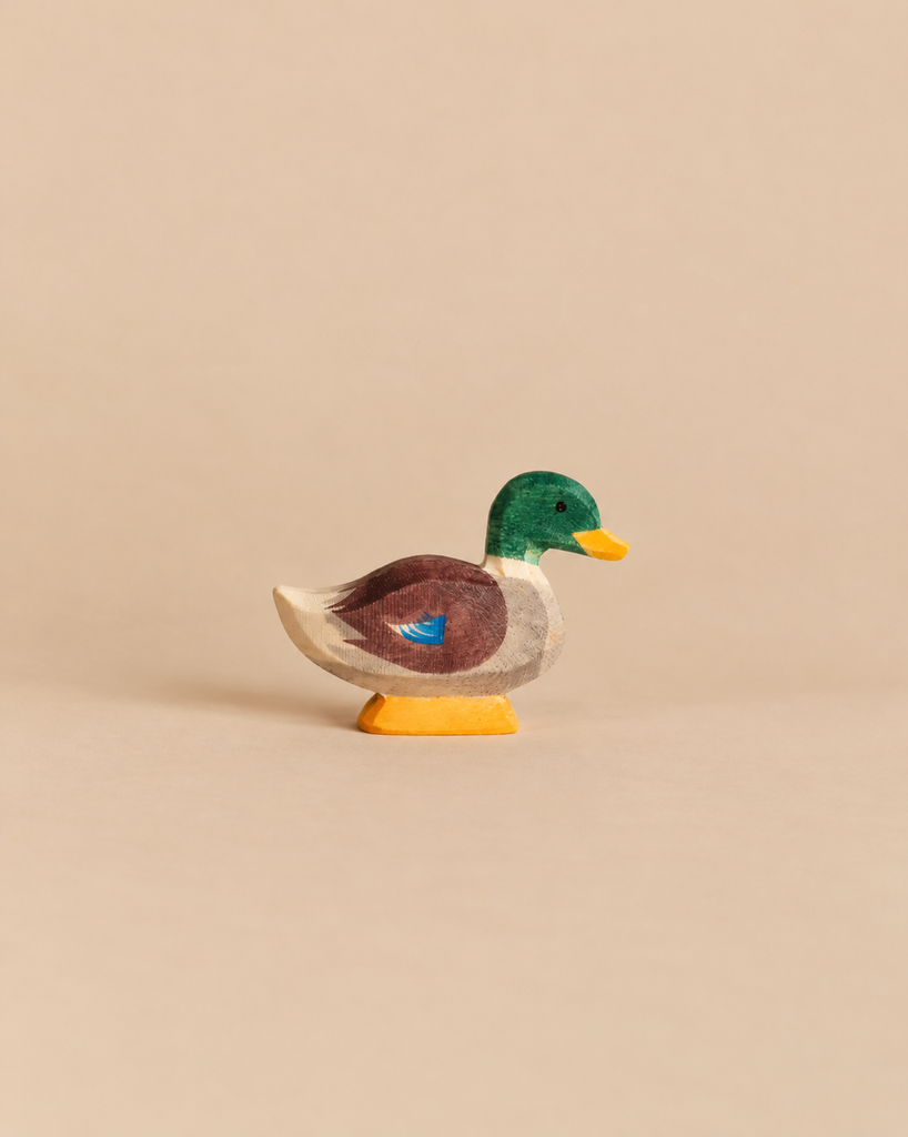 A small, handcrafted wooden Ostheimer Duck figure with a green head, brown body, and yellow feet.