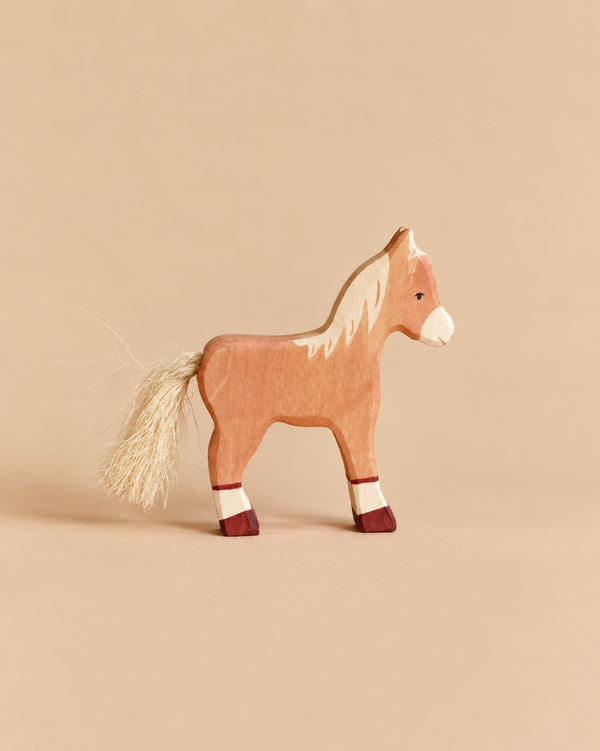 A handcrafted wooden Holztiger Horse Foal, Standing with a light-colored mane and tail, standing on four dark-tipped legs.