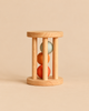 Sabo Concept Rolling Rattle - Lagoon wooden baby rattle featuring vertical dowels enclosing three stacked spheres in blue, orange, and terracotta.