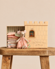 A Maileg Princess and The Pea, Big Sister Mouse doll in a floral dress sits next to its castle box filled with a stack of colorful fabric mattresses.