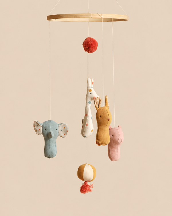 Maileg Lullaby Friends Mobile featuring a wooden hoop with hanging plush elephant, giraffe, rabbit, and pig toys, decorated with pom-poms and a striped ball to complement nursery decor.