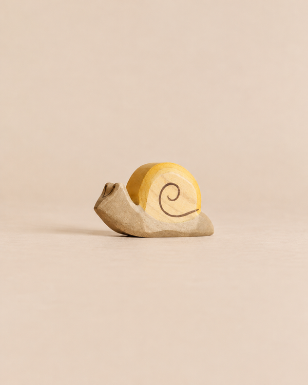A Handmade Holzwald Snail, a sustainable wooden toy featuring a yellow shell with a painted spiral.
