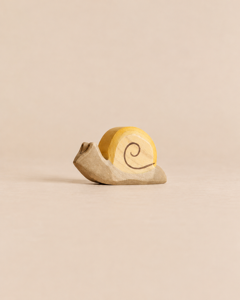 A Handmade Holzwald Snail, a sustainable wooden toy featuring a yellow shell with a painted spiral.